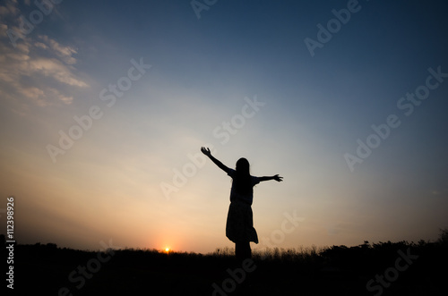 Silhouette of a girl gesture happy with the golden light of the sunset,