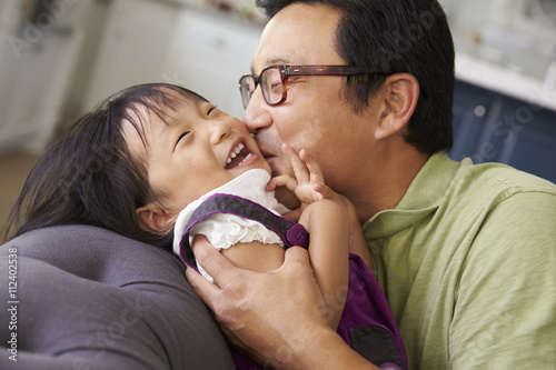 Affectionate Father And Daughter Relaxing On Sofa Together