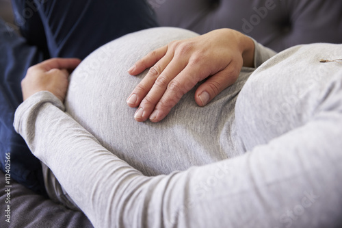 Close Up Of Pregnant Woman Relaxing On Sofa