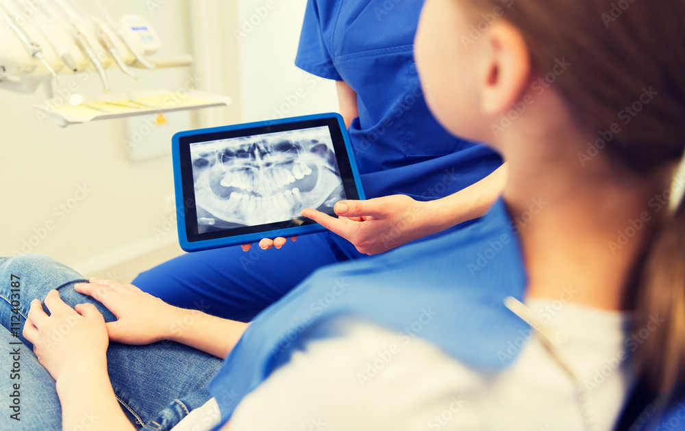 dentist showing x-ray on tablet pc to patient girl dentist showing x-ray on tablet pc to patient girl