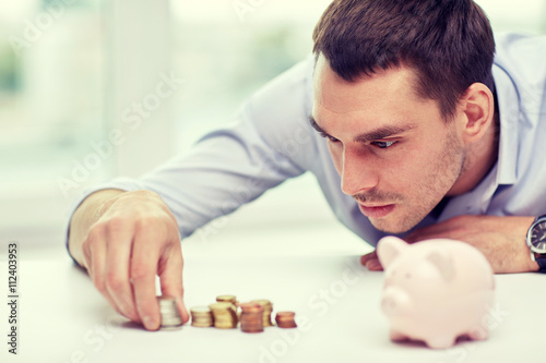 businessman with piggy bank and coins at office