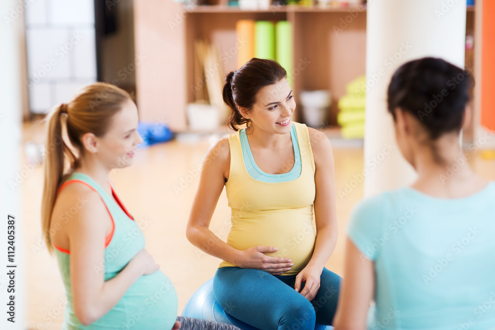happy pregnant women sitting on balls in gym