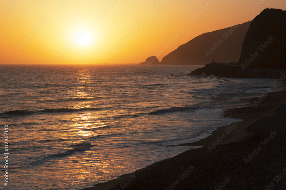 The Pacific ocean during sunset. Landscape with blue sea, the mountains and the dusk sky, the USA, California. 