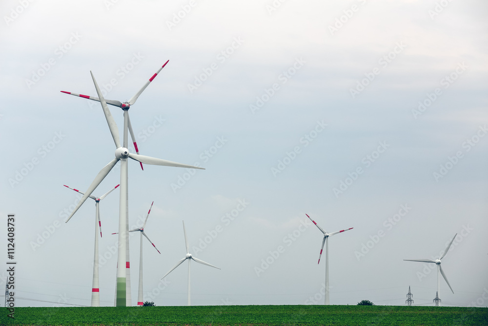 Ecological power with windmill on the field.Yard of windmill power generatorunder blue sky, shown as energy industry concept.Wind turbines generating electricity. Ecological power with windmill on the field.Yard of windmill power generatorunder blue sky, shown as energy industry concept.Wind turbines generating electricity.