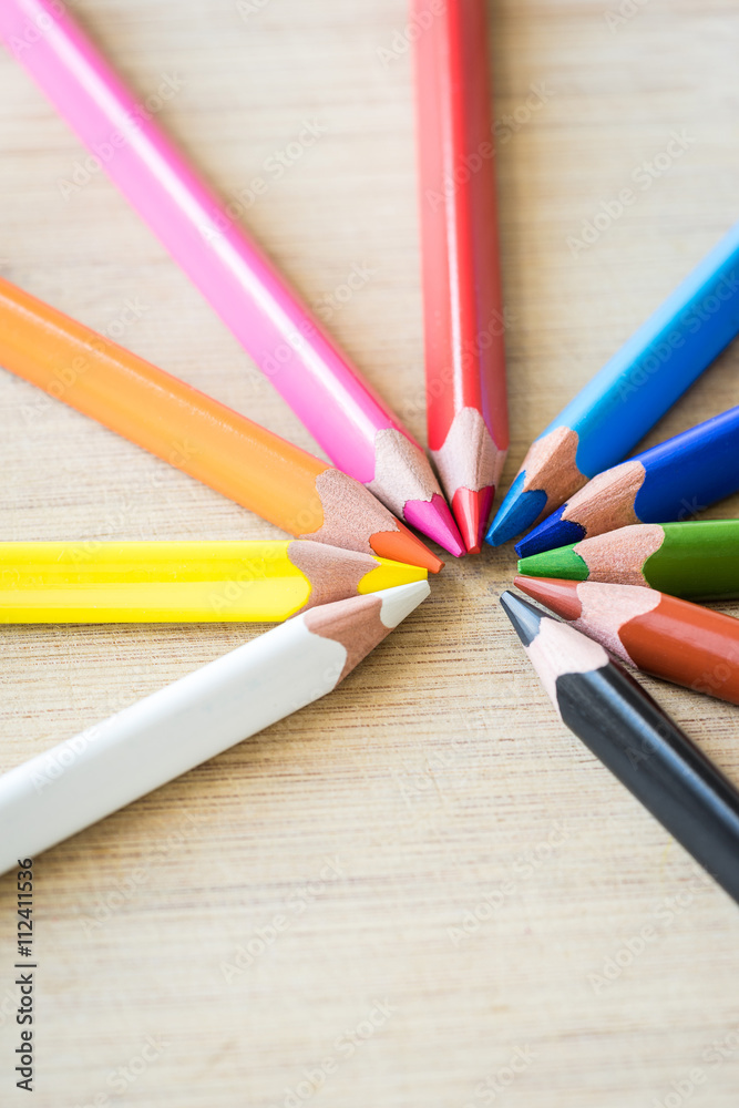 Fototapeta premium Color Pencils on wood texture. Macro shot of colorful pencils. Vertical view of pencils.