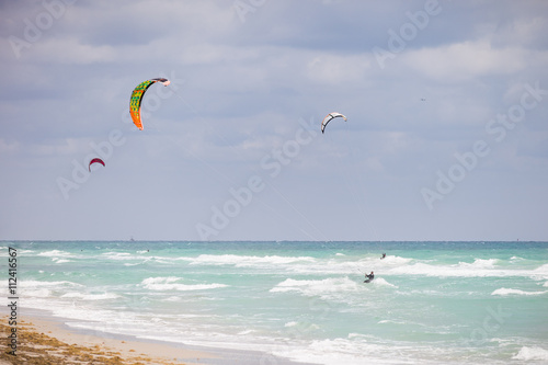 Beautiful view on the ocean beach with colorful kites. Cloudy day by the sea. Ocean coast. Vacation travel concept