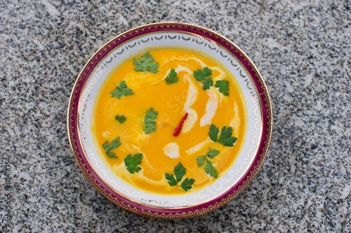 Sweet potato creamy soup asian or thai style vegan soup prepared from sweet potatoes or yam with chilli, curry, coconut milk, ginger, onion and fresh leaves of coriander. Fresh and spicy healthy food.