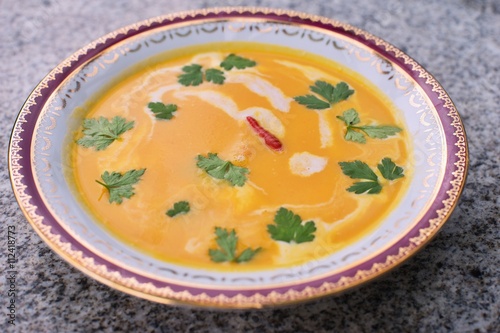 Sweet potato creamy soup asian or thai style vegan soup prepared from sweet potatoes or yam with chilli, curry, coconut milk, ginger, onion and fresh leaves of coriander. Fresh and spicy healthy food.
