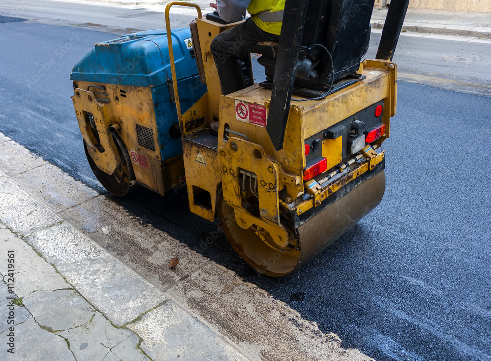 Light vibration roller compactor at asphalt pavement works for road repairing..On the frame are visible signs of job security: 
