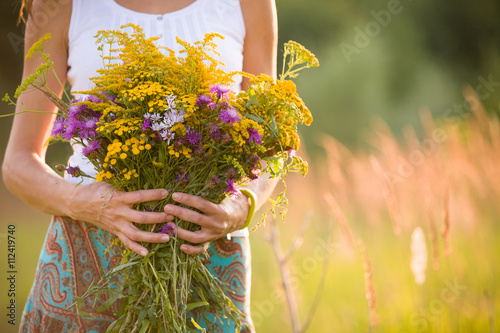 Vászonkép Closeup of woman's hands holding beautiful bunch of wild flowers on a sunny summer day