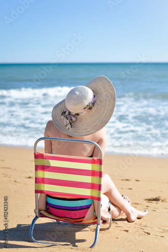 Rear view of woman in chair on summer time sun light beach holiday location