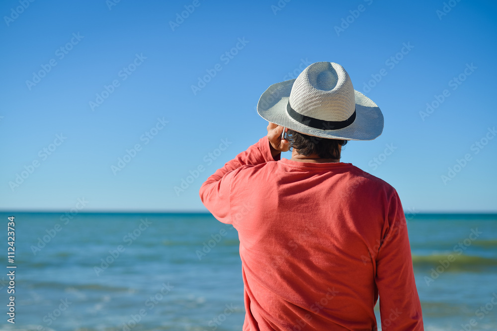 Person talking on cell phone looking at open water blue sky horizon, sunlight outdoors background. Person talking on cell phone looking at open water blue sky horizon, sunlight outdoors background.
