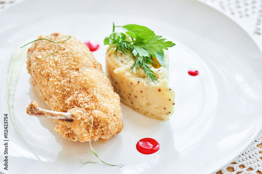Chicken Kiev fried in breadcrumbs, Parmesan sauce and mashed potatoes with Dijon mustard served on a white plate Chicken Kiev fried in breadcrumbs, Parmesan sauce and mashed potatoes with Dijon mustard served on a white plate