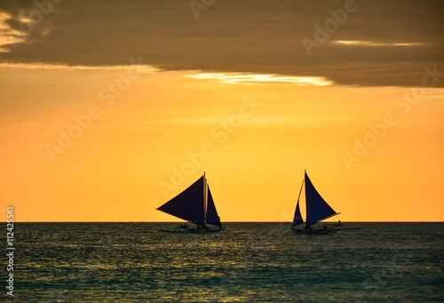 Boats with some tourists watching the sunset from the sea 