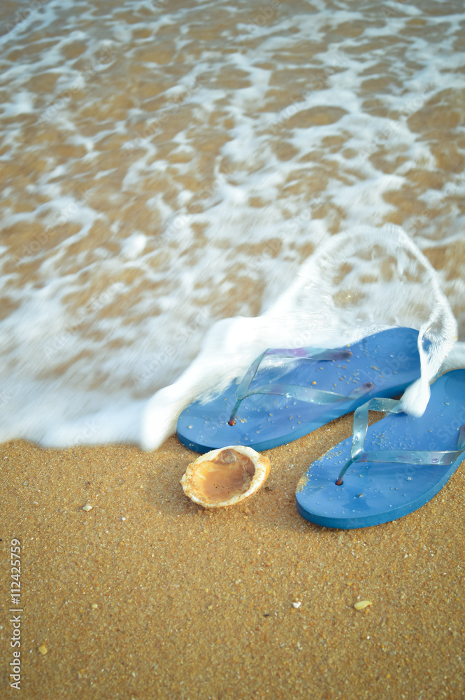 Blue flip flops and ocean shell along tropical exotic beach. Top view close up Blue flip flops and ocean shell along tropical exotic beach. Top view close up