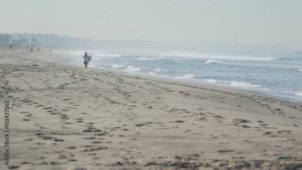 Surfer walks beach near the Santa Monica Pier. Surfer walks beach near the Santa Monica Pier.