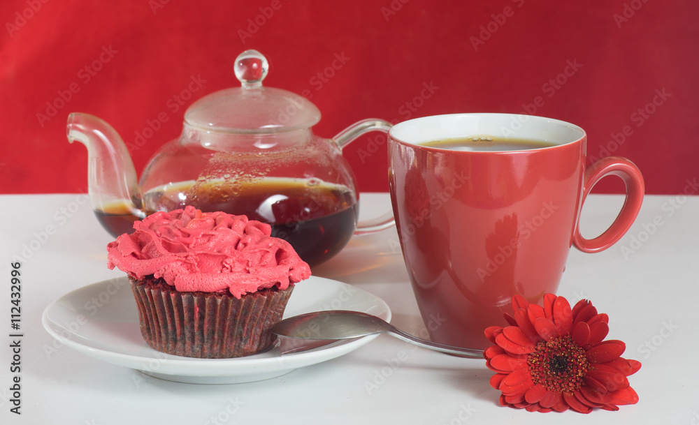 Cup of tea and teapot with red gerbera flower