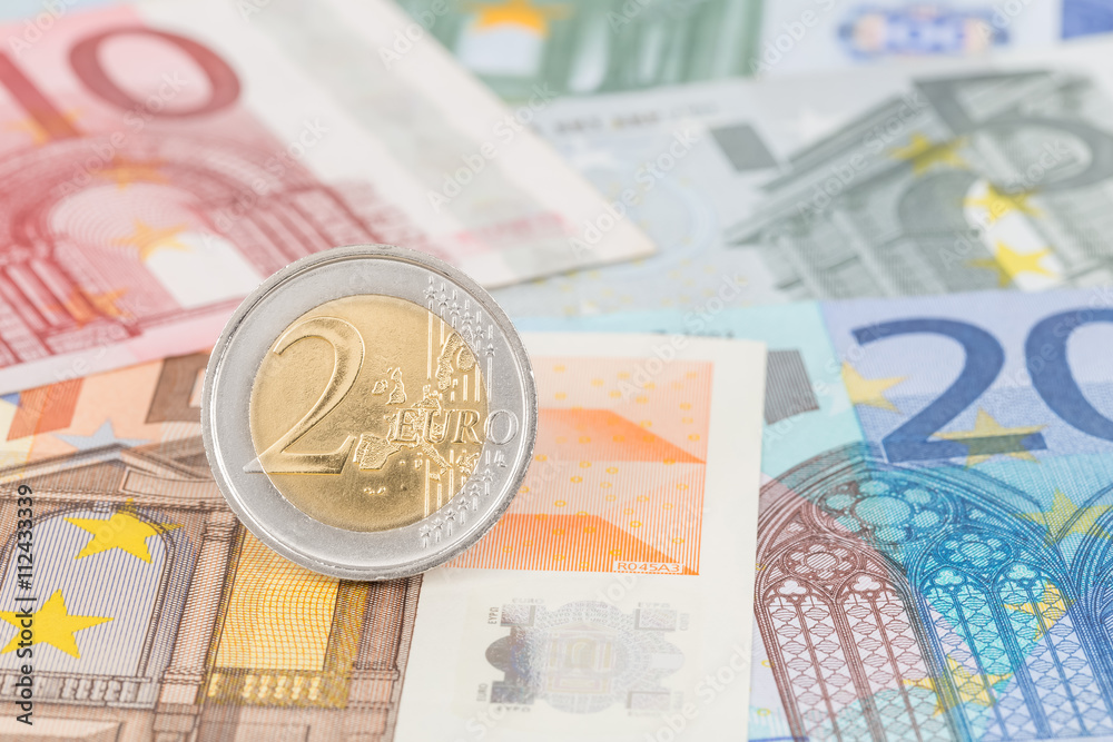 Two euro coin stand on banknote money Two euro coin stand on banknote money