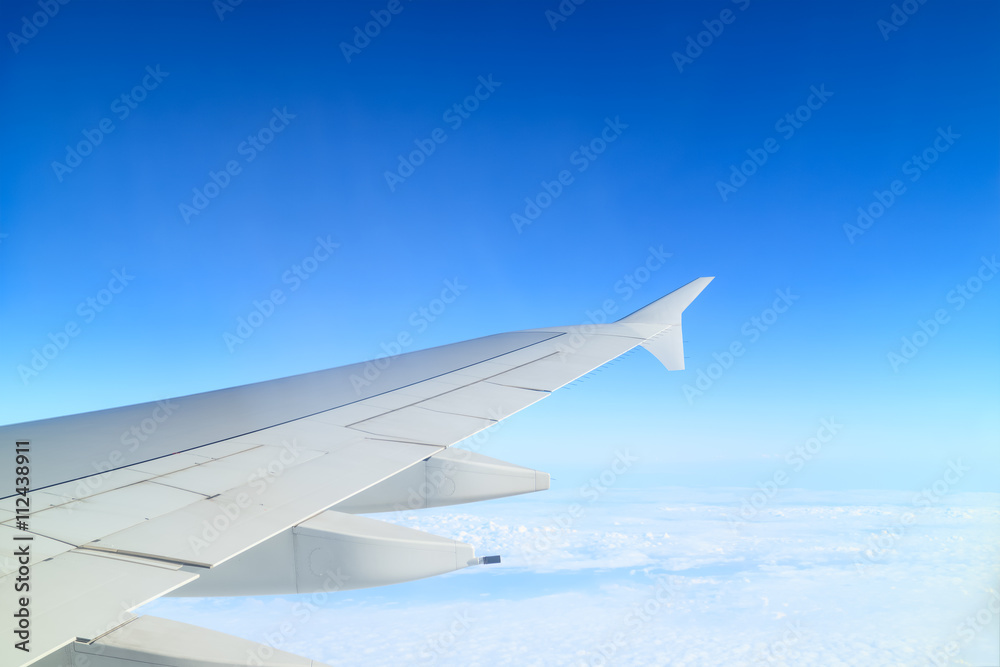 Airplane wing above cloud seen through window Airplane wing above cloud seen through window