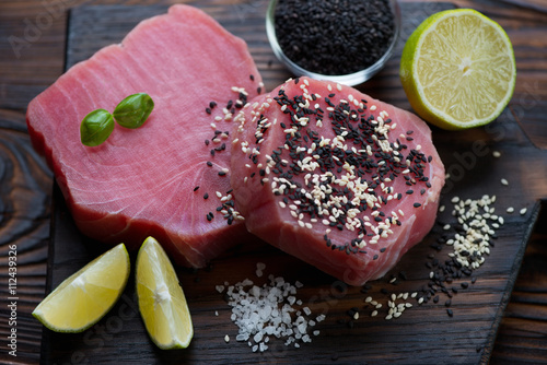 Close-up of raw tuna steaks with sesame seeds and condiments