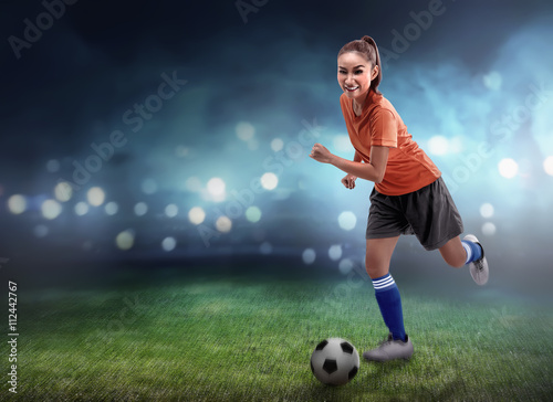 Female football player dribbling ball © Leo Lintang