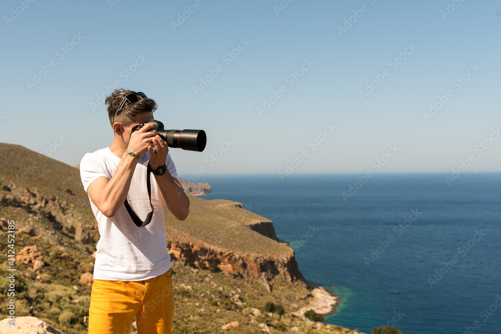 man taking a picture of the landscape against the sea man taking a picture of the landscape against the sea