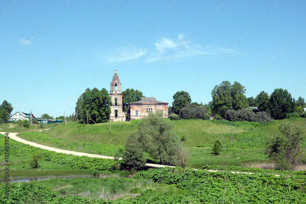 Countryside landscape with hills, river, a village and christian church ruins far away on sunny summer day