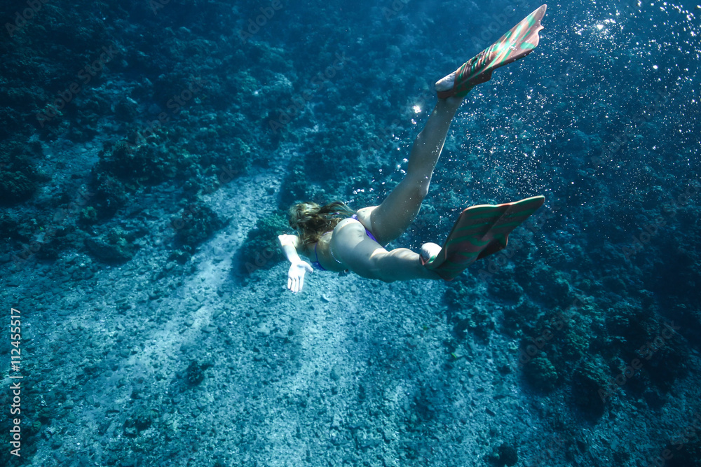 Sexy woman in bikini with a nice ass dives to the bottom of the ocean in flippers