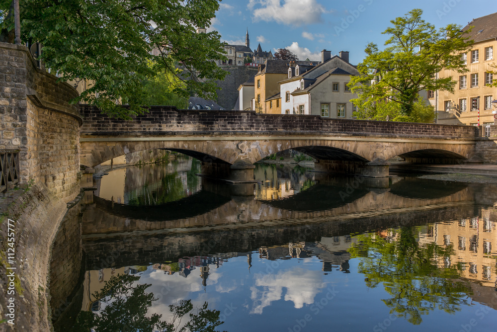 Stone bridge reflecting in the Alzette river in the city of Luxe