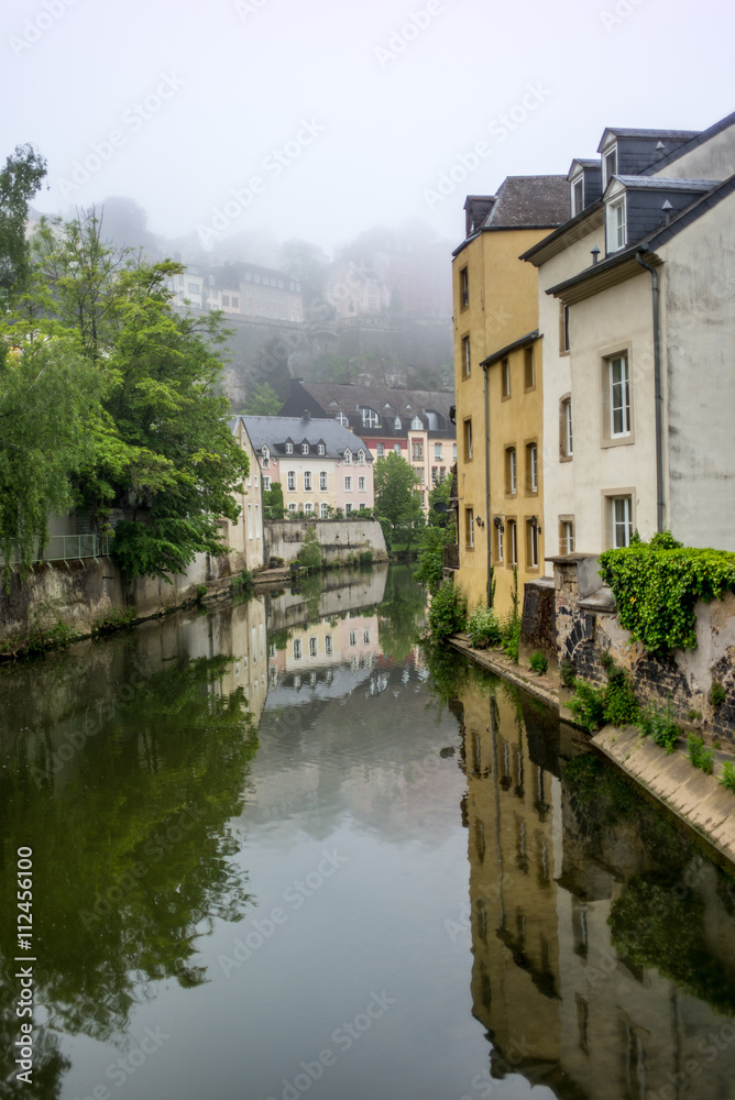 Colorful buildings reflecting in the Alzette river in the city o