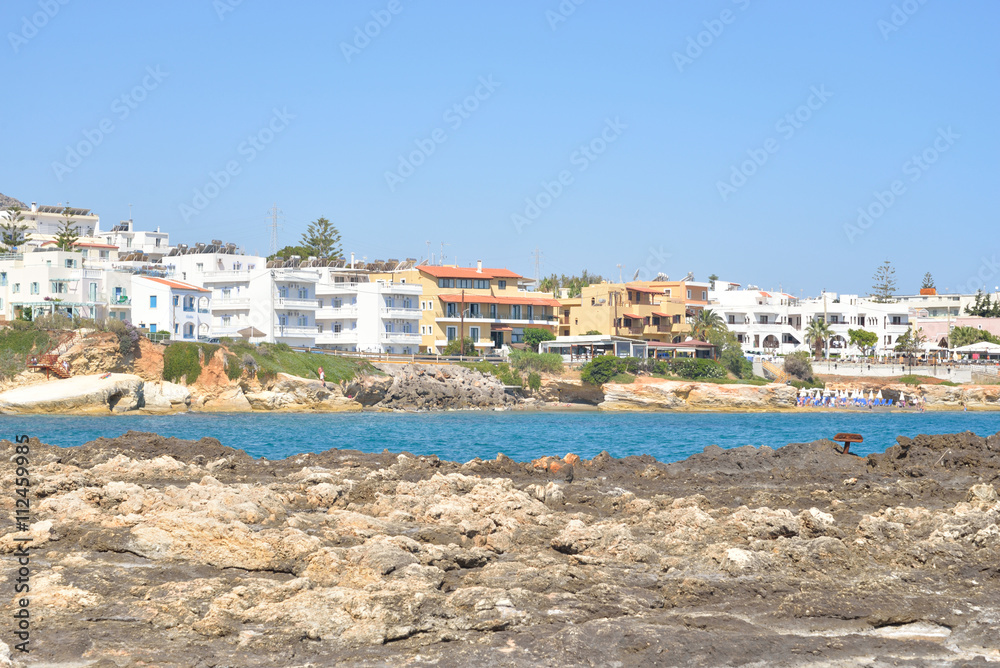 Rocks on the shore of the sea and the city of Hersonissos.