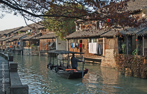 Shanghai, Wuzhen historic scenic town old houses and boat for tourists along a canal. 