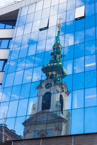 Reflection of old church in modern building windows, Stiftskirche, Mariahilferstrasse, Vienna photo