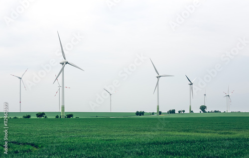 Wind turbines generating electricity for the city. Group of eco windmills for renewable electric energy production. Ecological power with windmill on the field