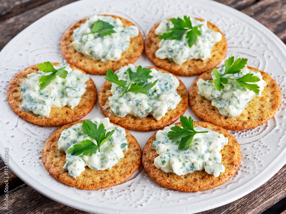 Bisquit cracker appetizers with cottage chees and parsley topping