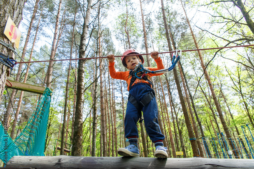 Young boy in helmet walks by pendant tree log Young boy in helmet walks by pendant tree log