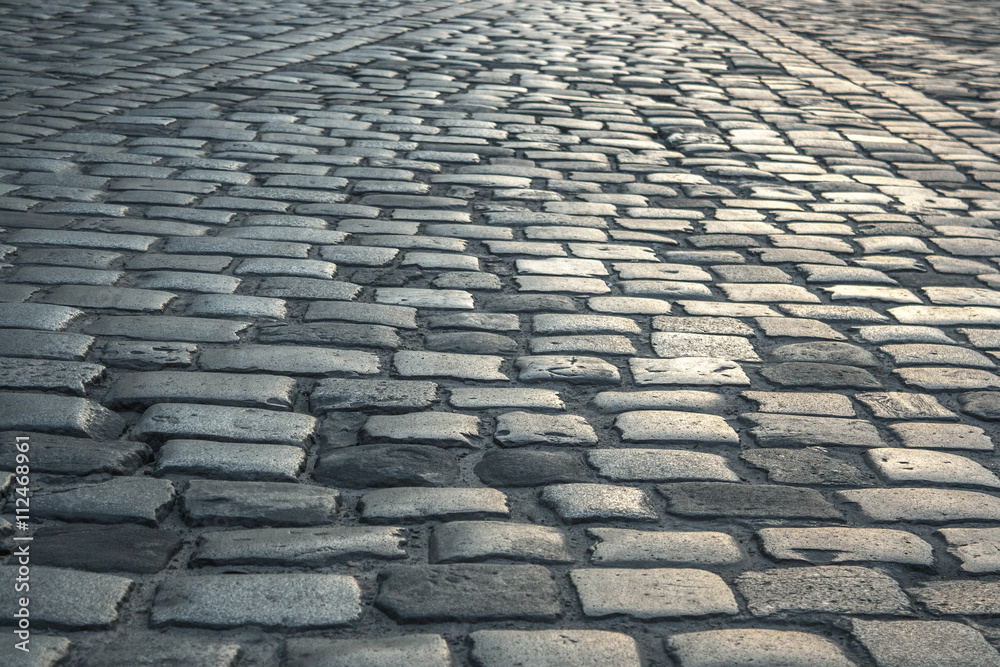 background of old road paved with granite stones background of old road paved with granite stones