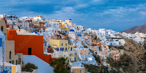 Panoramic view of white houses, windmills and church with blue domes in Oia or Ia, island Santorini, Greece
