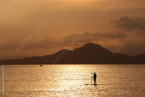 Silhouette of a paddle board surfer in the sunset