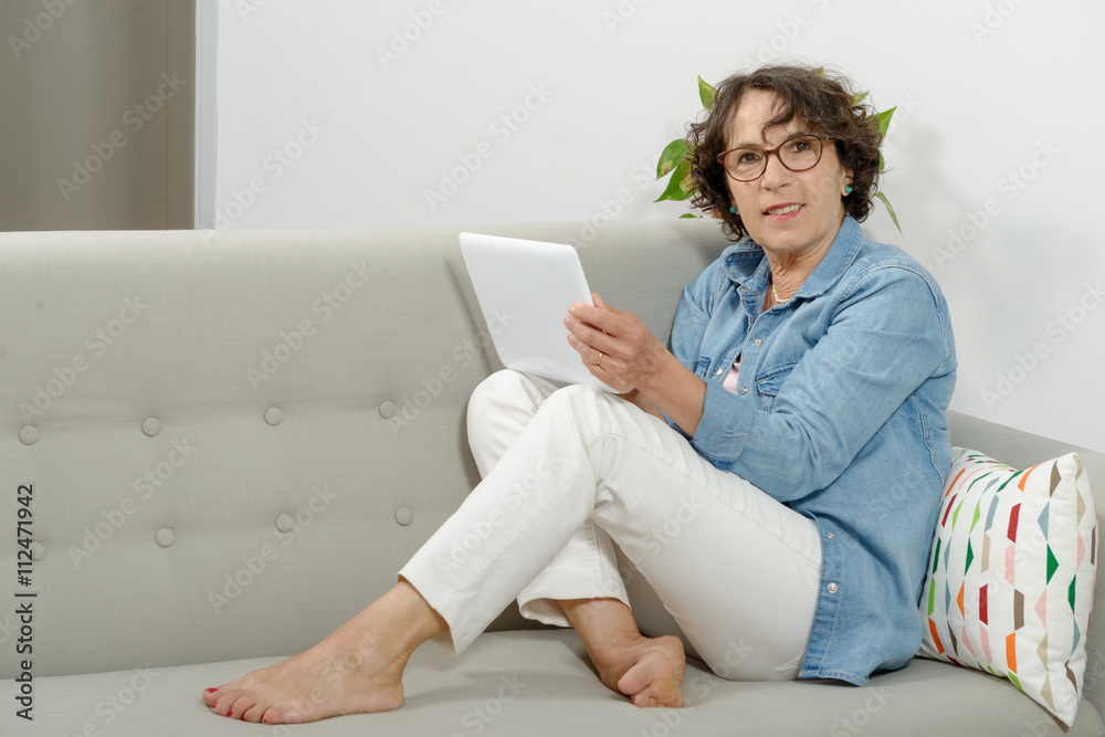 mature woman with a tablet on the sofa Stock Photo | Adobe Stock