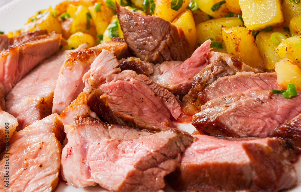 Sliced medium rare grilled Steak Ribeye with potato in a plate on wooden table Sliced medium rare grilled Steak Ribeye with potato in a plate on wooden table