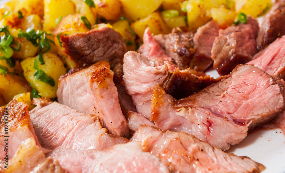 Sliced medium rare grilled Steak Ribeye with potato in a plate on wooden table Sliced medium rare grilled Steak Ribeye with potato in a plate on wooden table