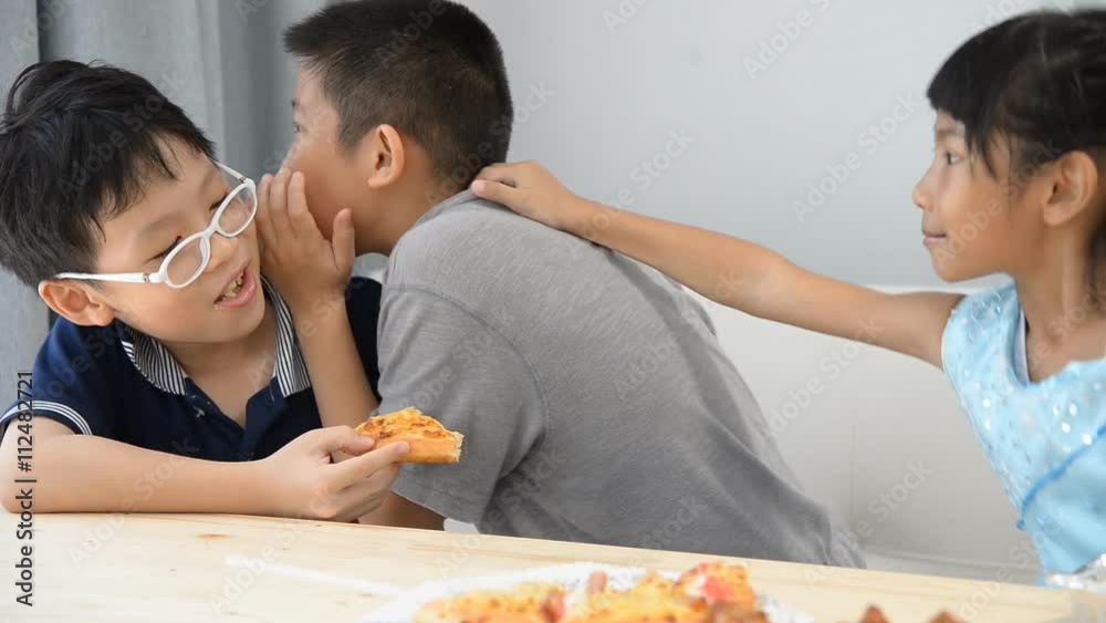 Asian boy whisper to his friend during their lunch at home Asian boy whisper to his friend during their lunch at home