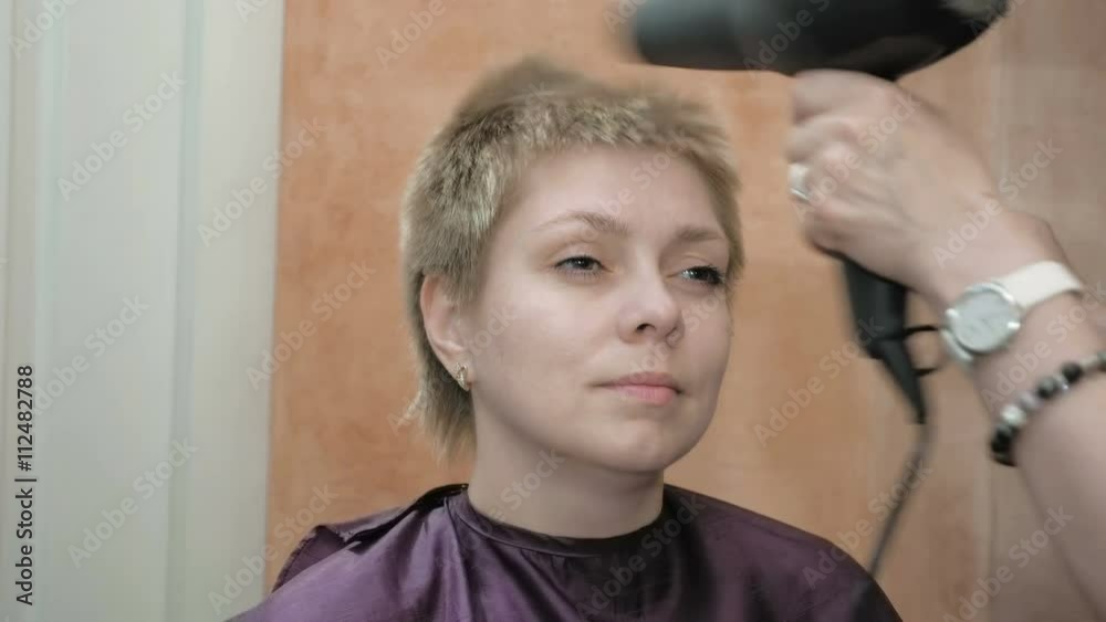 Hairdresser dries and styles pretty blond woman short hair with fan dryer comb and various tools. Beauty spa and makeup salon studio scene. 4K UHD video footage. Hairdresser dries and styles pretty blond woman short hair with fan dryer comb and various tools. Beauty spa and makeup salon studio scene. 4K UHD video footage.