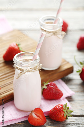 Strawberry yogurt in bottle on wooden table