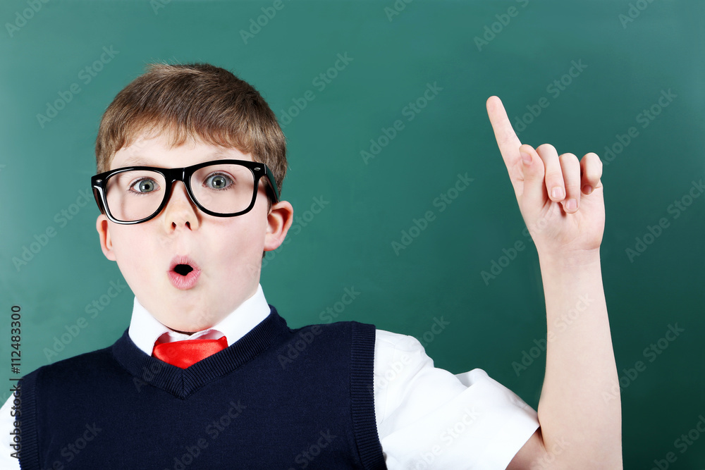 Young boy standing near the blackboard, close up