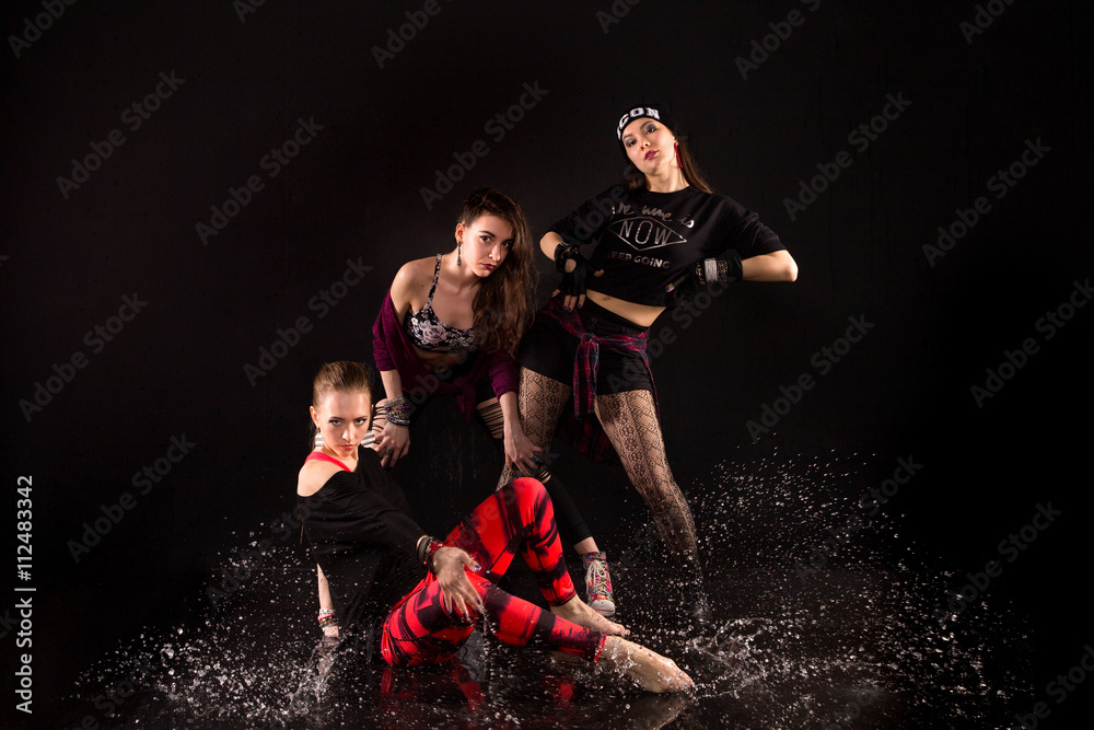 hip-hop team of beautiful girls dancing on the water. studio with black background