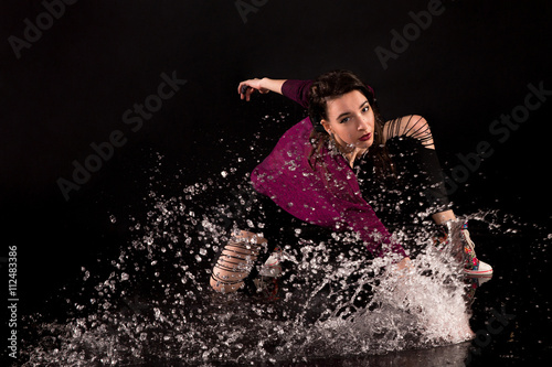 brunette in a street-style dancing in the water splashing among. studio with black background