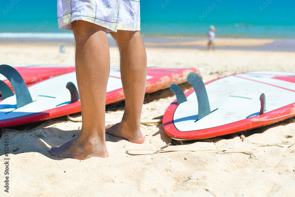Legs of athlete and surfboards on the sand background. Closeup Legs of athlete and surfboards on the sand background. Closeup