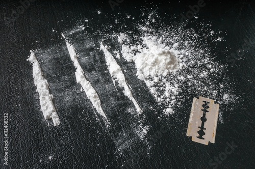 Cocaine white powder in lines and razor. Narcotics concept. photo